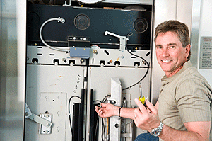 An elevator repair technician looks at a control panel for a new elevator.