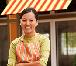 A store owner stands under her custom window awning after new awning installation.