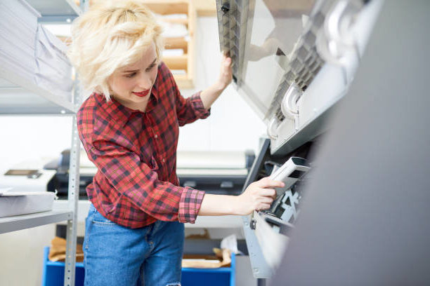A professional printer sets up an offset printer before printing custom wedding invitations.