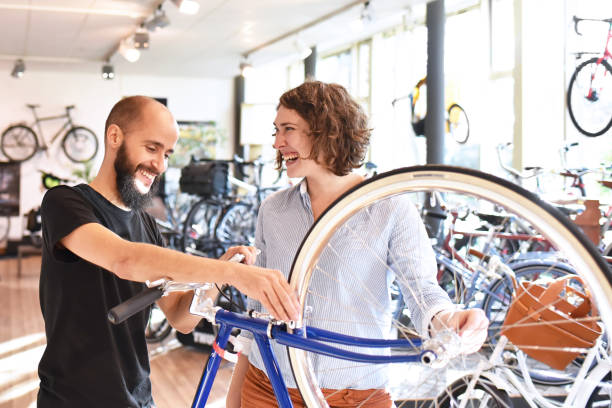 A local bike store employee shows a customer new and used bicycles for sale.