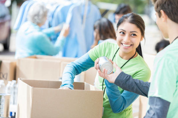 Two volunteers show their dedication to local community nonprofit organizations by packing boxes at a local food bank.