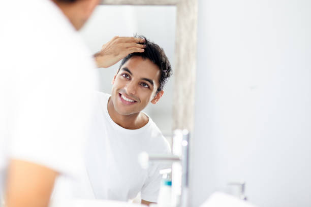 A man admires his new hair restoration after completing hair loss treatments.
