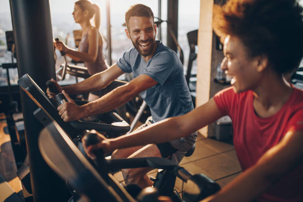 Health club members encourage each other as they use the stationary bicycles as part of their fitness club workout.