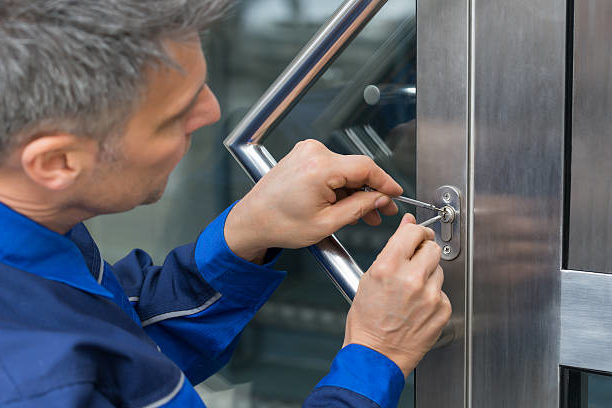 A locksmith installs a new locking mechanism on a client's front door.