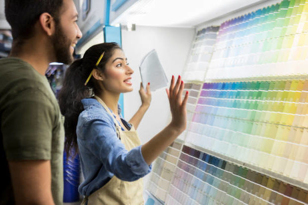 A paint store employee helps a homeowner pick out new interior paint for his home from paint samples.