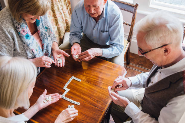 A group of friends plays dominoes at their senior living center and retirement community.