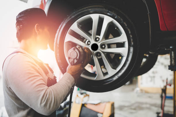 A tire store employee installs new tires and hubcaps on a client's vehicle.