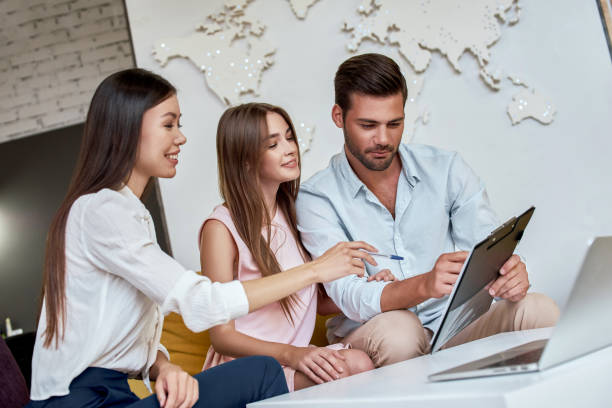 A couple meets with their local travel agent to discuss plans for a honeymoon and overseas vacation.