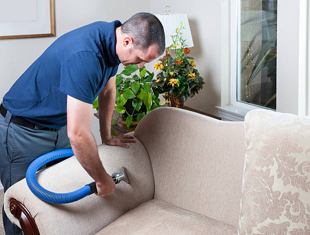 An upholstery cleaning contractor uses a steam vacuum to clean a couch as part of upholstery repair and upholstery shampooing services.